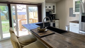 A modern kitchen with a central island, a built-in oven, and a stainless steel refrigerator. - Modern Ranch Studio With a Beautiful Round Porch (Cocoa)