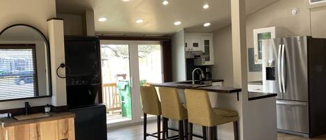 A compact kitchen with a refrigerator, a sink, and a bar area with stools.