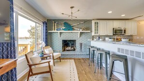 A modern kitchen with a fireplace, bar stools, and a view of the outdoors. - Spacious Lakefront Home in White Lake (White Lake Charter Township)