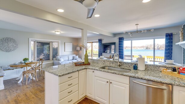 A modern kitchen with granite countertops, white cabinetry, and a stainless steel dishwasher. - Spacious Lakefront Home in White Lake (White Lake Charter Township)