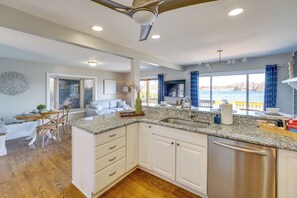 A modern kitchen with granite countertops, white cabinetry, and a stainless steel dishwasher. - Spacious Lakefront Home in White Lake (White Lake Charter Township)