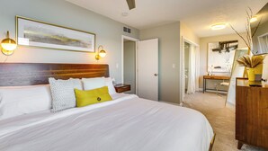 A neatly made bed with white and yellow pillows, a wooden headboard, and a framed picture above it. - Spacious Lakefront Home in White Lake (White Lake Charter Township)