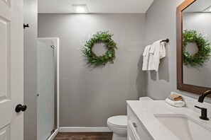 A bathroom with a white toilet, a sink with a mirror, and two green wreaths on the wall. - Abenteuer Haus in downtown Leavenworth! (Leavenworth)