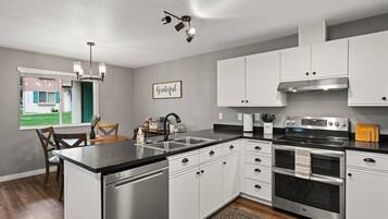 A modern kitchen with stainless steel appliances, white cabinetry, and a central island.