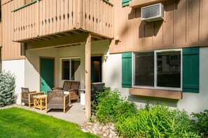 Ein Gebäude mit überdachter Terrasse, Außenbereich mit Sitzgelegenheiten und einem kleinen Garten.