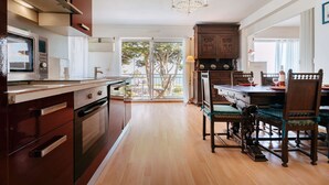Een keuken met moderne apparaten, een eethoek met houten meubels en uitzicht op de omgeving.