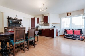 A spacious living area with a dining table, chairs, a sofa, and a kitchen in the background.
