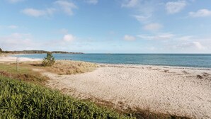Een strand met een heldere lucht, zandstrand en een verre horizon.