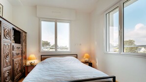 Een slaapkamer met een bed, twee bedlampen, een kledingkast en een raam met uitzicht.