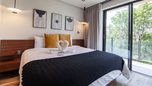 Ein modernes Hotelzimmer mit einem großen Bett, zwei goldenen Kissen und drei gerahmten Kunstwerken an der Wand.