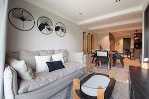 Ein modernes Wohnzimmer mit Sofa, Couchtisch und Essbereich.
