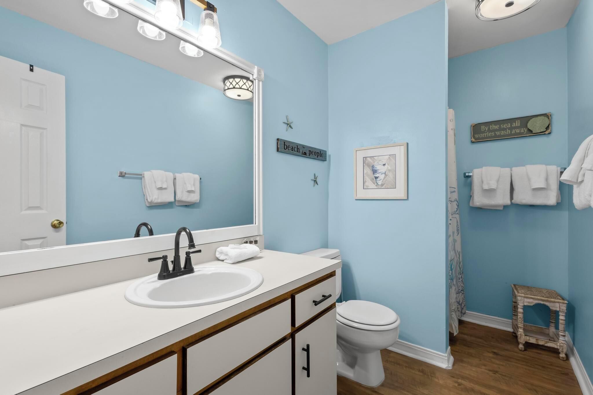 A bathroom with a white sink, a large mirror, a toilet, and a shower curtain.