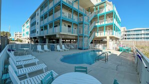 A multi-story hotel with a pool area, outdoor seating, and balconies. - BEACH-FRONT CONDO, OUTDOOR POOL, PRIVATE BALCONY! (Gulf Shores)
