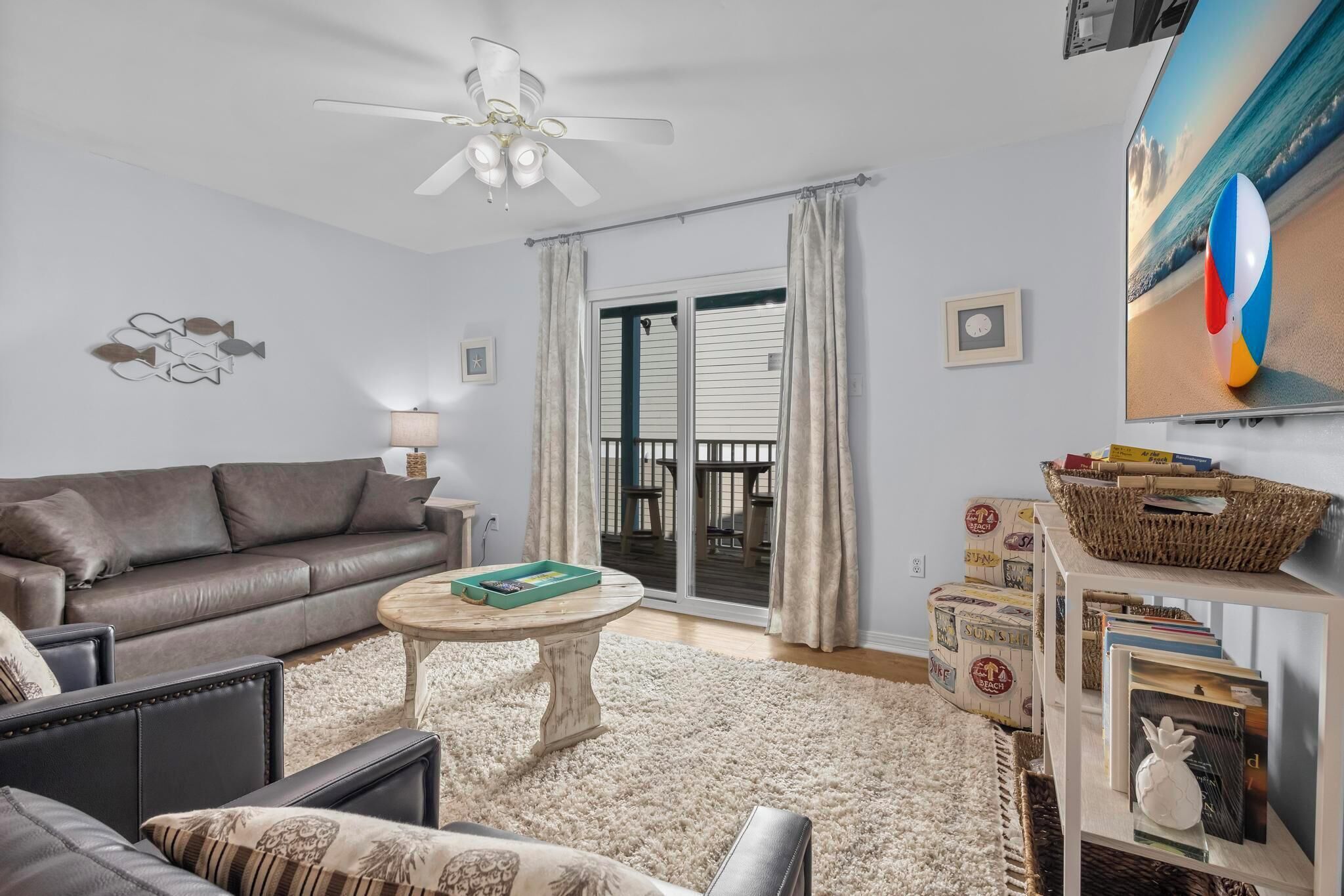 A living room with a sofa, coffee table, and a TV displaying a beach scene.