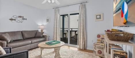 A living room with a sofa, coffee table, and a TV displaying a beach scene.