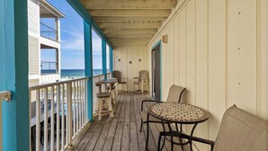 A covered balcony with wooden flooring, a round table with chairs, and a view of the ocean. - BEACH-FRONT CONDO, OUTDOOR POOL, PRIVATE BALCONY! (Gulf Shores)