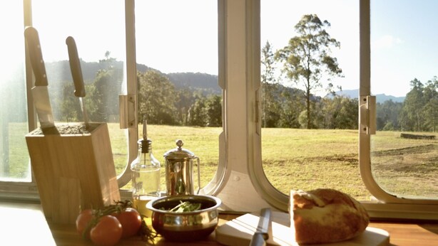 A kitchen counter with a knife block, a bottle, a pot, a cutting board, and a loaf of bread. - Coffee Grounds - The Bus (Coffee Camp)