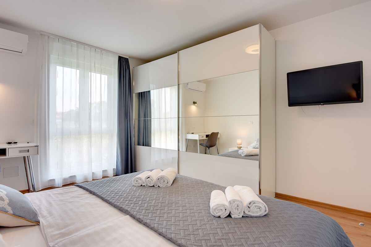 Een moderne hotelkamer met een groot bed, een bureau, een flatscreen televisie en een grote spiegel.
