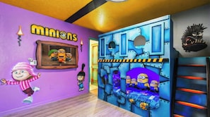Una stanza con una parete viola, un quadro incorniciato con i Minions, una grande struttura giochi blu e un letto a tema Minion.