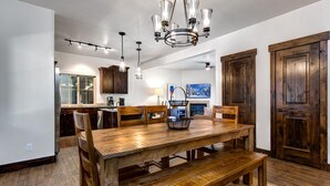 A dining area with a wooden table and benches, a chandelier, and wooden doors. - Gym  Hot Tub & Seasonal Outdoor Pool  Bike Trail  Parking Garage (Park City)