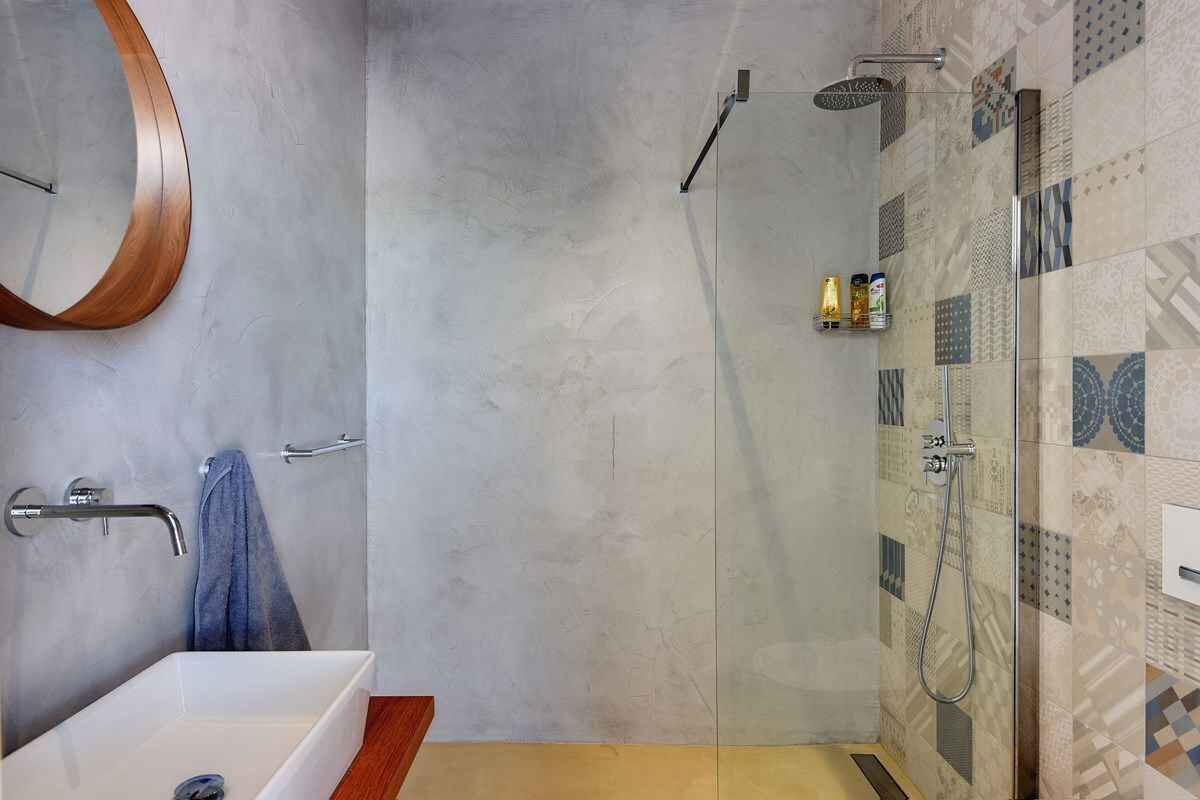 Een moderne badkamer met een glazen douchecabine, een witte wastafel en een houten aanrecht.