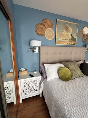 Una camera da letto con un letto, comodini, una lampada, un quadro e decorazioni a parete.