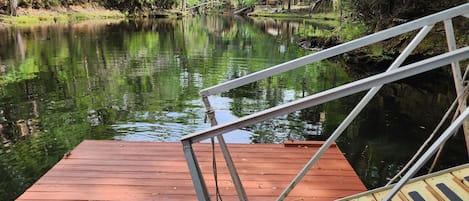 A wooden dock extending into a calm river surrounded by lush greenery.