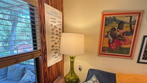 Una habitación con pared de paneles de madera, un cartel de peces de agua dulce de Florida, una lámpara, un sofá con cojines estampados y un cuadro enmarcado.
