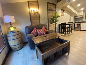 A living room with a wooden coffee table, a sofa with patterned cushions, a lamp, and a potted plant.
