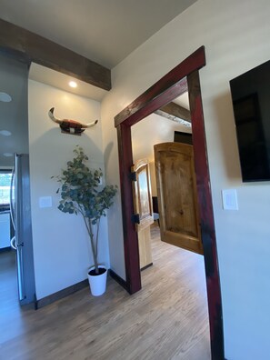 A hallway with a wooden door, a potted plant, and a wall-mounted decorative item.