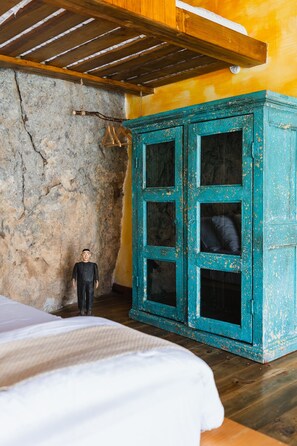Ein rustikaler Raum mit Holzbalkendecke, Steinwand und einem türkisblauen Schrank mit mehreren Schubladen.