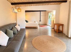 Una habitación moderna con sofá, cama, alfombra tejida y mesa de madera.