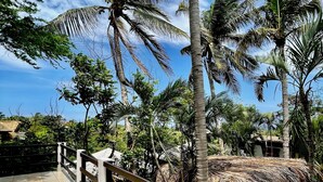 A tiled terrace with a railing, surrounded by palm trees and a thatched structure. - El Eden Escondido (Puerto Escondido)