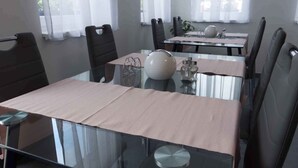 Un espace repas moderne avec des tables en verre et des chaises noires, agrémenté d’un élément décoratif central et de plantes disposées sur les tables.