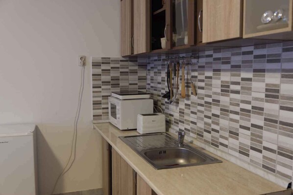 A kitchen with a tiled backsplash, a microwave, a toaster, and a sink.