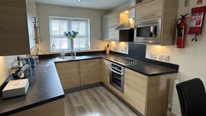 Una cucina moderna con mobili in legno, un piano di lavoro nero, elettrodomestici in acciaio inossidabile e una finestra con persiane.