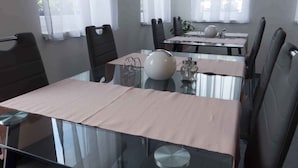 Ein moderner Essbereich mit Glastischen und schwarzen Stühlen, mit einem zentralen Dekorationsobjekt und Pflanzen auf den Tischen.