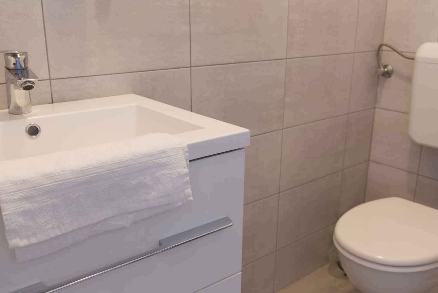 Un bagno con lavandino bianco, asciugamano e water.