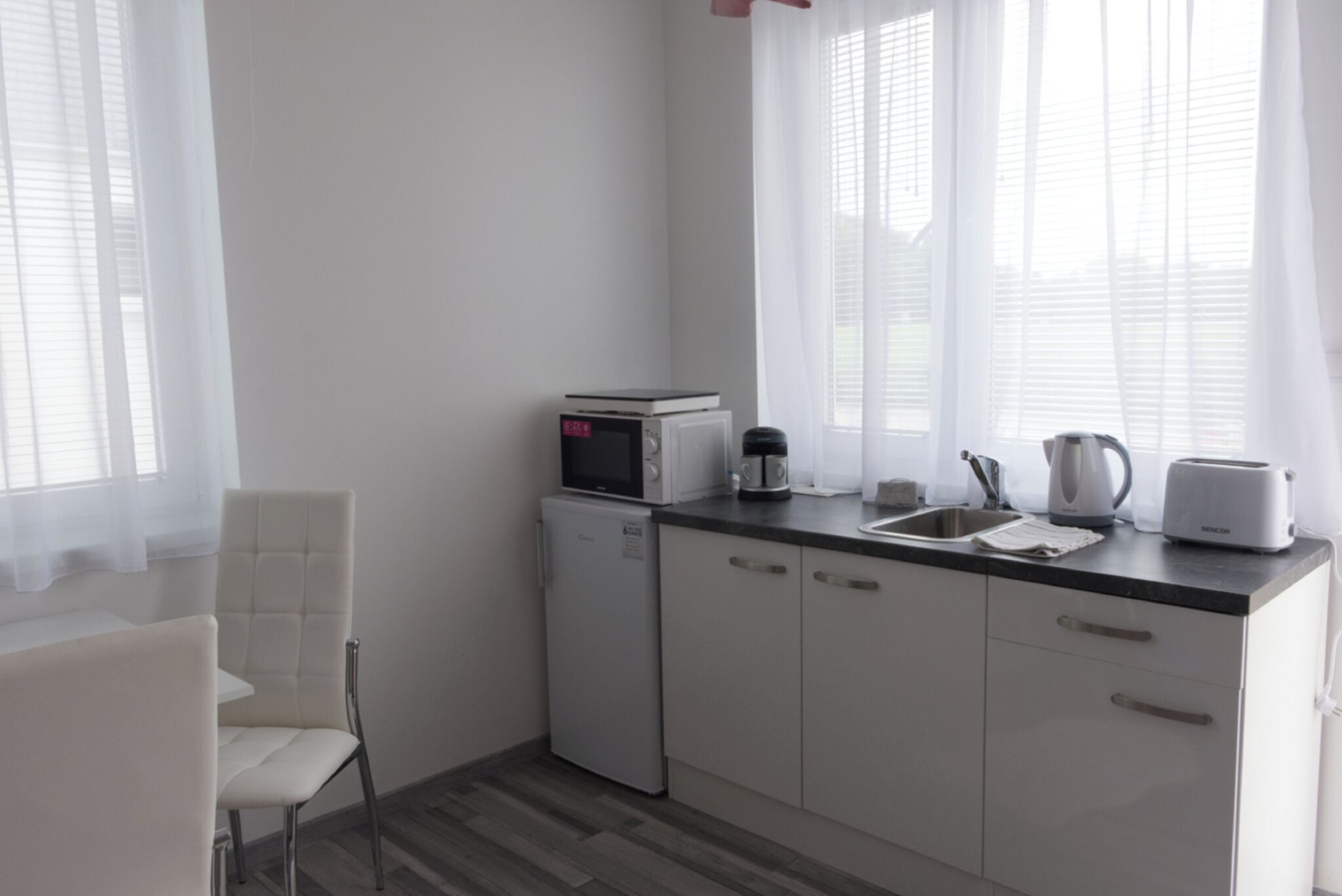 Eine kleine Küchenzeile mit Mikrowelle, Kaffeemaschine, Toaster und Spüle.