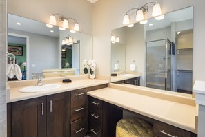 Une salle de bain moderne avec deux vasques, des meubles en bois foncé et un grand miroir.