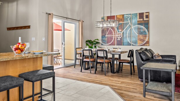 A modern kitchen with a bar area, dining space, and a large bicycle artwork on the wall. - New Listing: Private Spa | Sunroom | Pool | Garage | Close to Parks | C347 (Moab)