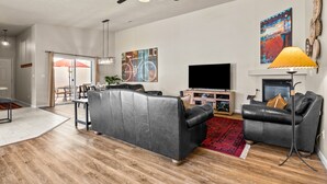 A modern living room with a grey leather sofa, a flat-screen TV, and a ceiling fan. - New Listing: Private Spa | Sunroom | Pool | Garage | Close to Parks | C347 (Moab)