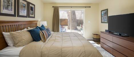 A bedroom with a large bed, a TV, a dresser, and framed pictures on the wall.
