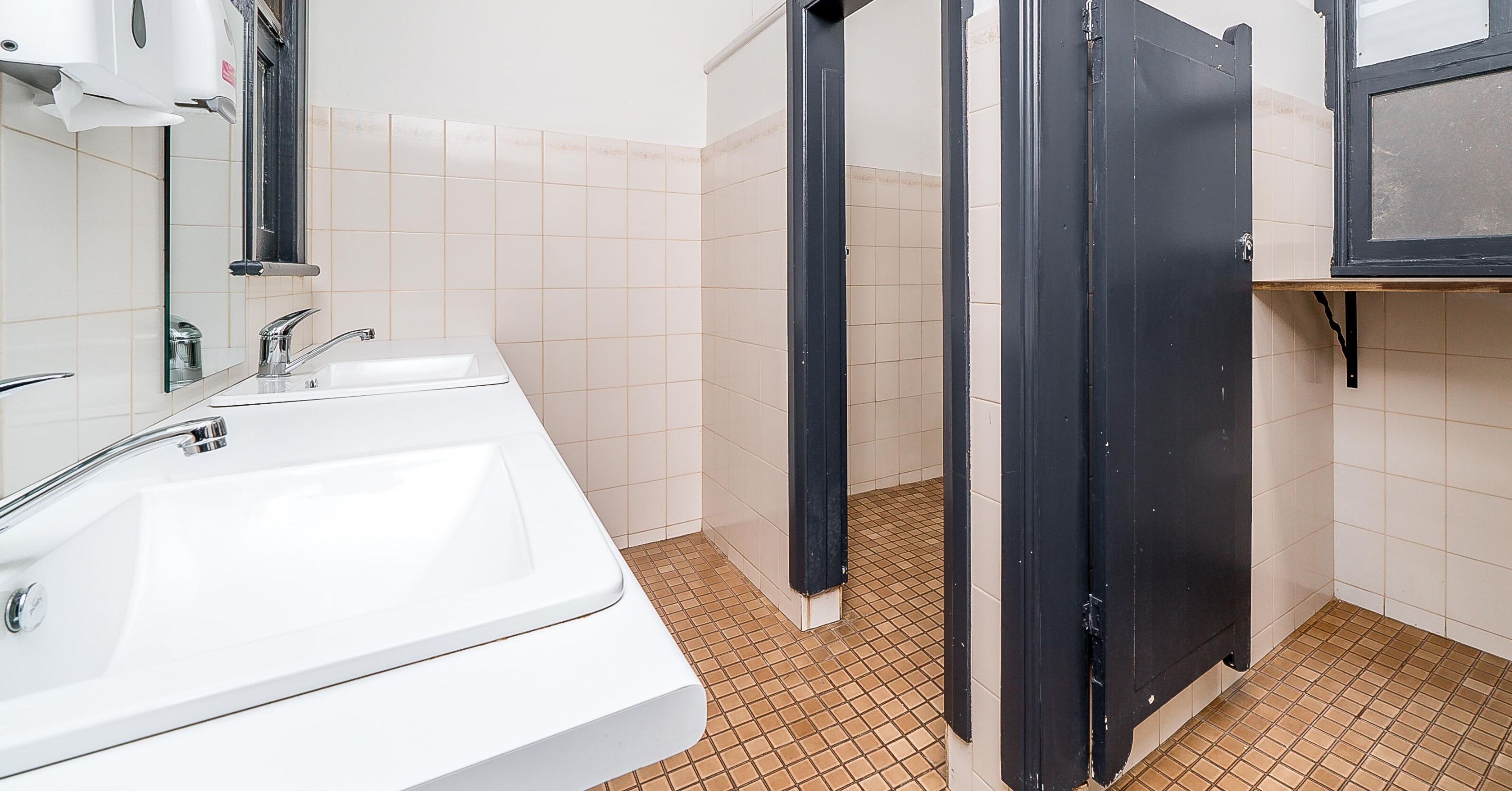 A bathroom with a white sink, a mirror, and a shower area with a black door.