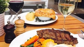 Taula de dinar amb un plat de filet, verdures i un pa, acompanyat de dues copes de vi.
