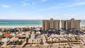 Een kusthotel met meerdere gebouwen, een parkeerplaats en uitzicht op het strand.