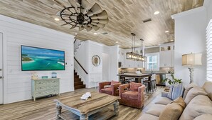 Un salón espacioso con una mesa de centro de madera, un sofá color beige y un televisor montado en la pared.