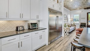Una cocina moderna con armarios blancos, un refrigerador de acero inoxidable y una encimera con una tostadora.