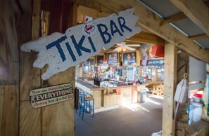 A wooden interior with a sign reading "TIKI BAR" and a sign below stating "Those who think they know EVERYTHING annoy those of us that do." - Four Sails - Oceanfront & City View Balconies! (Virginia Beach)