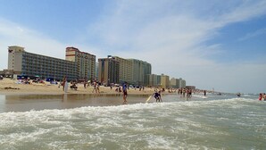 A beachside hotel with multiple high-rise buildings, sandy beach, and ocean waves. - Four Sails - Oceanfront & City View Balconies! (Virginia Beach)